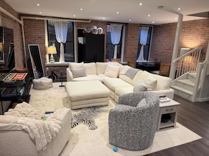 A living room with a sectional sofa, a zebra-patterned armchair, a small table, and a staircase. - Prime West Village 3BR/2.5BA  Available Nov 9–Jan 31  30+ Night Stays (New York)