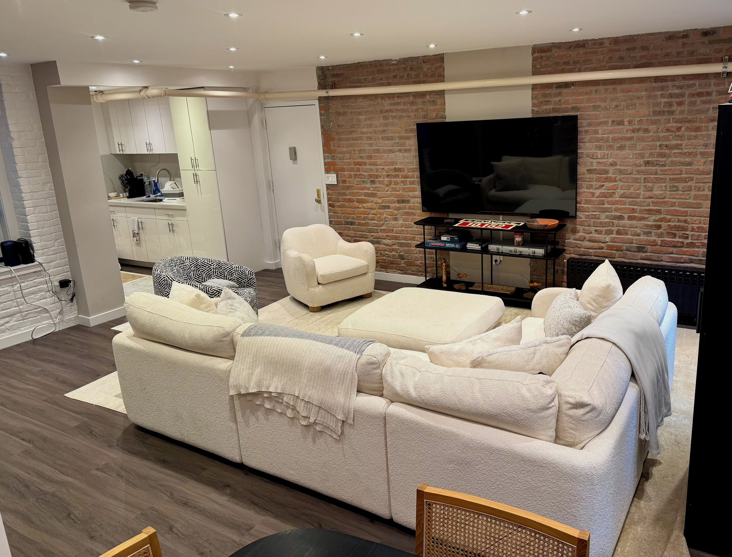 Una sala de estar moderna con un sofá, sillones, un televisor y una pared de ladrillo.