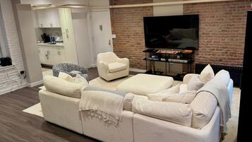 Una sala de estar moderna con un sofá, sillones, un televisor y una pared de ladrillo.