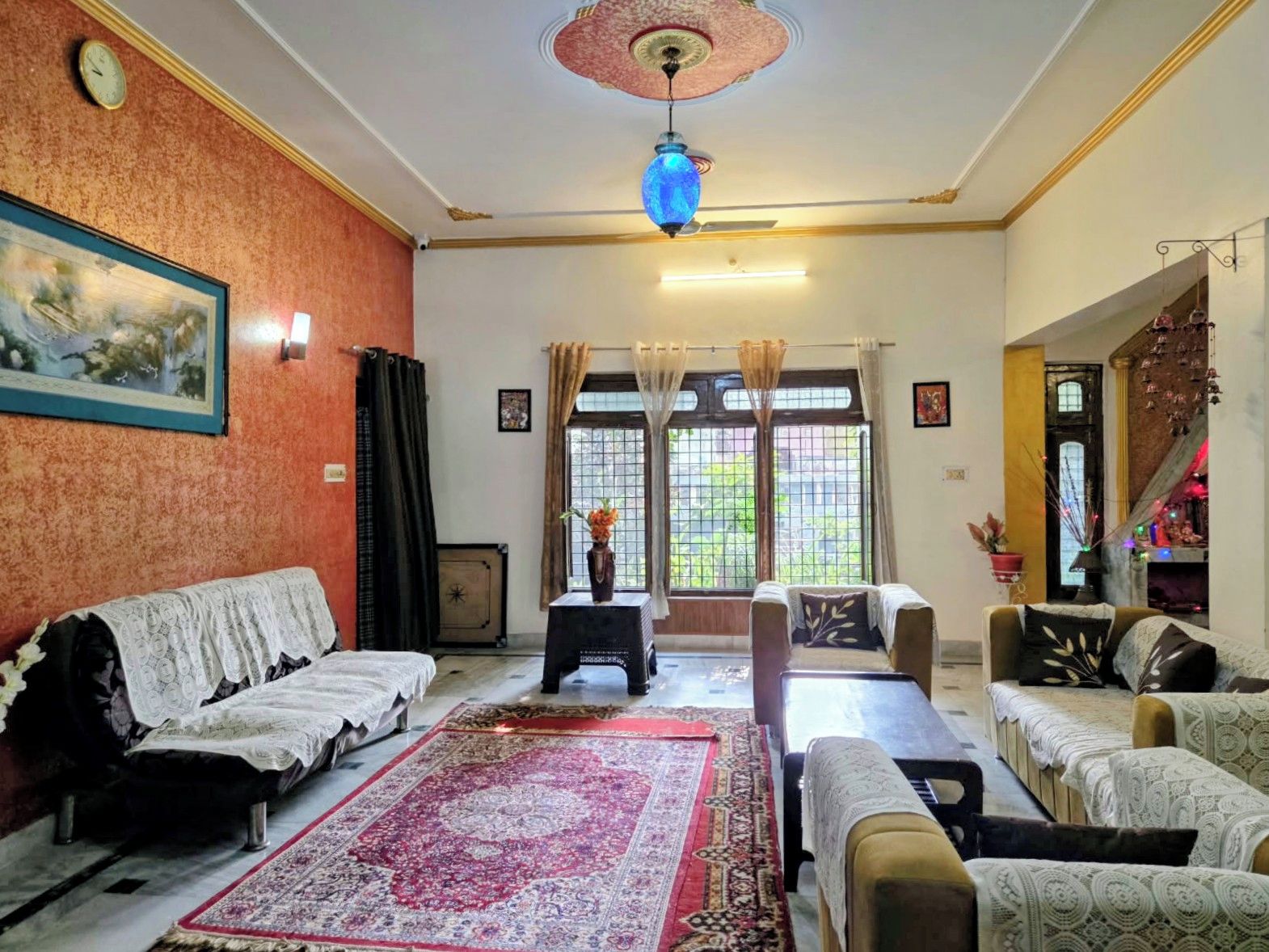 A living room with a sofa set, a coffee table, a patterned rug, and a ceiling fan.