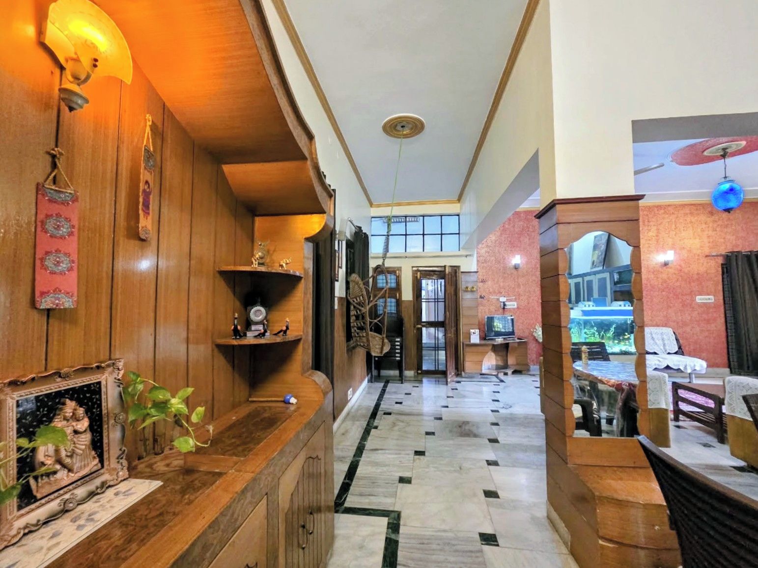A hotel lobby with a wooden reception desk, a clock, and a decorative wall.