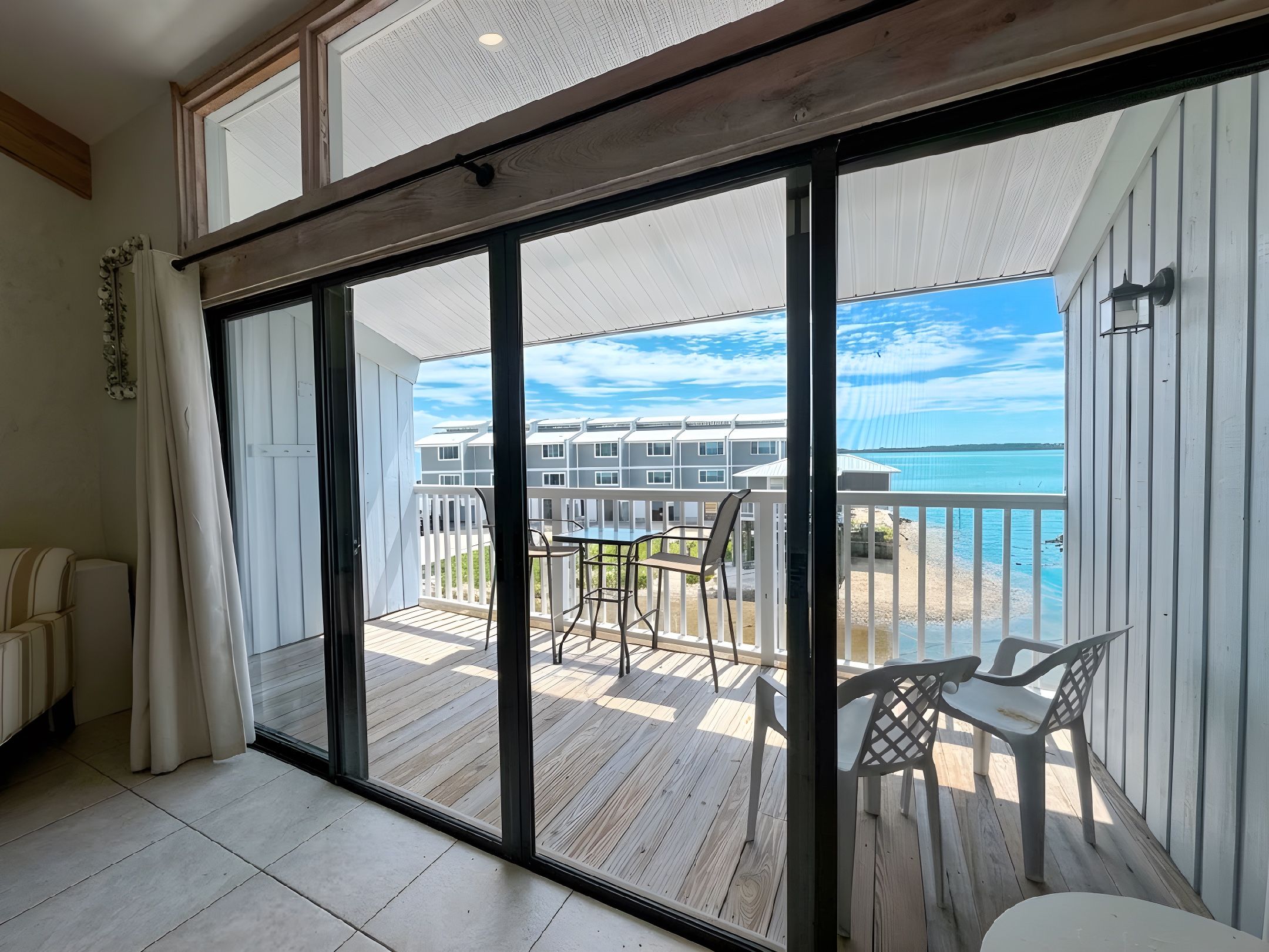 A spacious balcony with a view of the sea and a wooden deck.