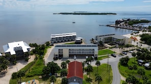 A coastal property with a marina, modern buildings, and a beach. - Seven C's at Cedar Cove! Waterfront Loft, Covered Balcony & Downtown! (Cedar Key)