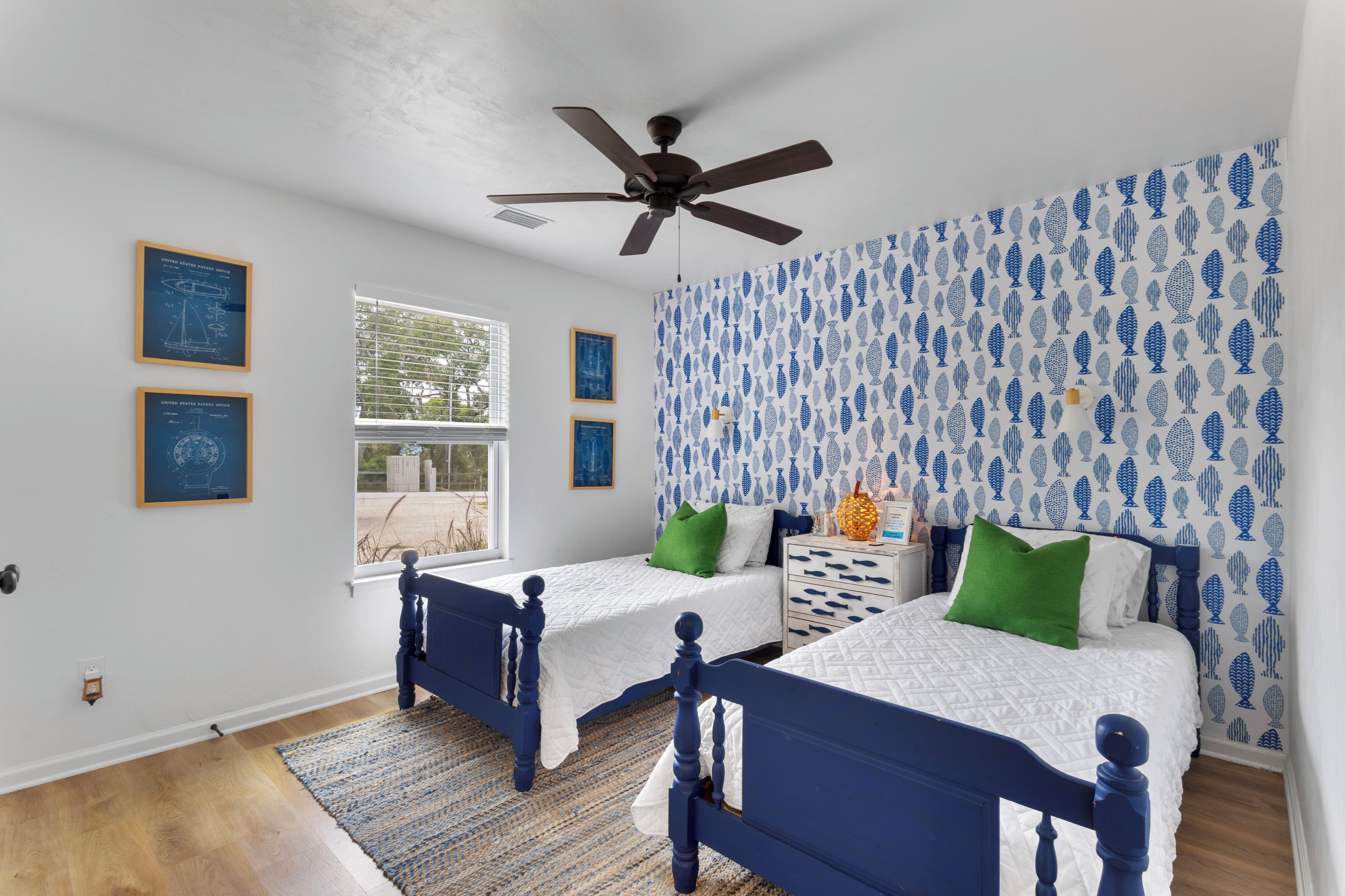 A bedroom with two beds, a ceiling fan, and a window with blinds.
