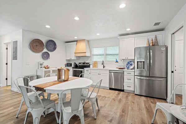 Una cocina moderna con armarios blancos, electrodomésticos de acero inoxidable y una isla central con sillas.