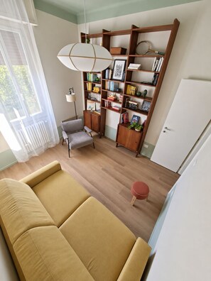 A living room with a sofa, a chair, a bookshelf, and a radiator. - Your stay in Bologna, just a stone's throw from Sant'Orsola, the city center, and the fairgrounds (Bologna)