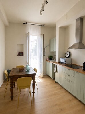 A kitchen with a dining table, chairs, a microwave, and a sink. - Your stay in Bologna, just a stone's throw from Sant'Orsola, the city center, and the fairgrounds (Bologna)