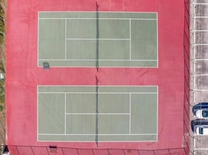 A tennis court with a net in the center, surrounded by a red surface. - Winter Escape on the Water in Crystal River (Crystal River)
