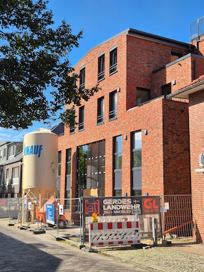 A red brick building with multiple windows and a large cylindrical tank labeled 'KNAUF'. - Old Town Apartment - The Vacation Rental in the Center of Sulingen (Sulingen)
