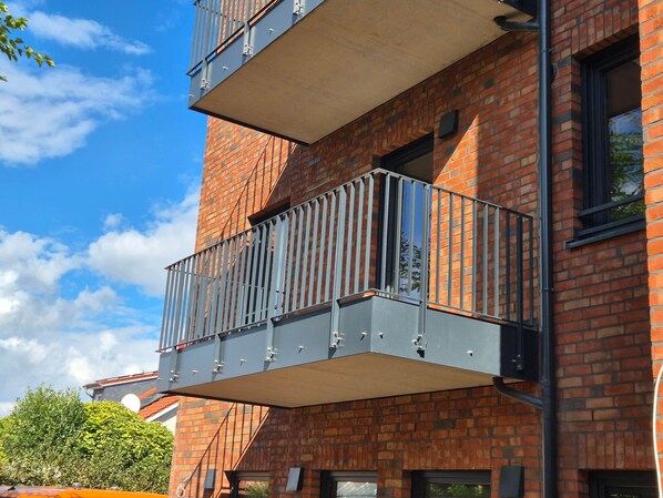 A multi-story building with a brick facade and balconies with metal railings. - Old Town Apartment - The Vacation Rental in the Center of Sulingen (Sulingen)