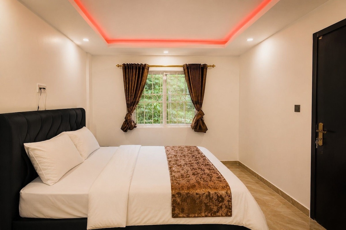 A bedroom with a bed, curtains, a window, and a door.
