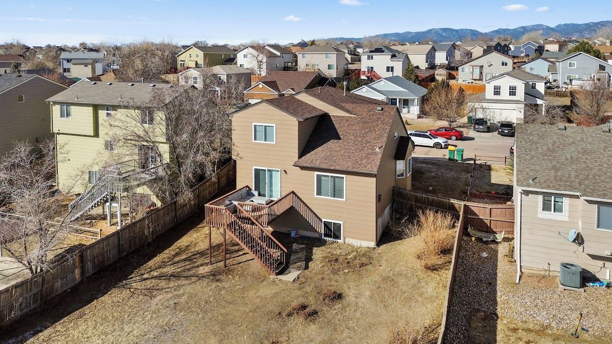 A residential area with houses, a wooden deck, and a staircase leading to a second floor.