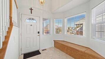 A hallway with a white door, a bench, and multiple windows with blinds.