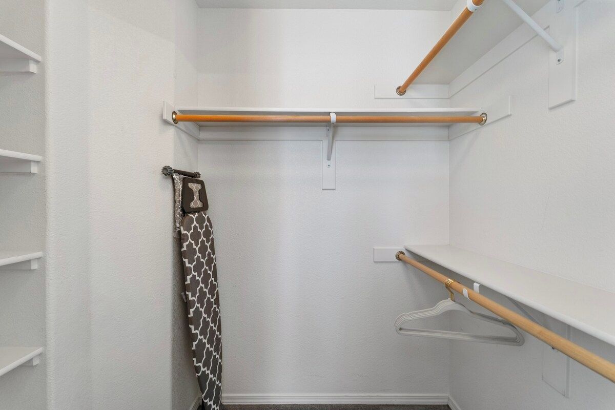 A walk-in closet with wooden rods, a patterned towel, and white shelves.