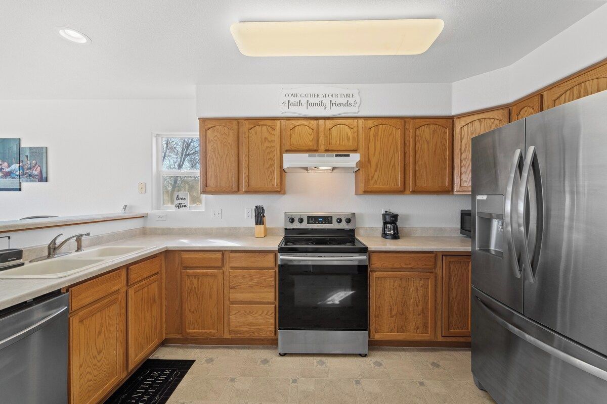 A modern kitchen with wooden cabinets, stainless steel appliances, and a central island.