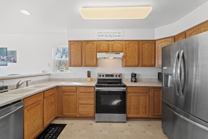Una cocina moderna con armarios de madera, electrodomésticos de acero inoxidable y una isla central.