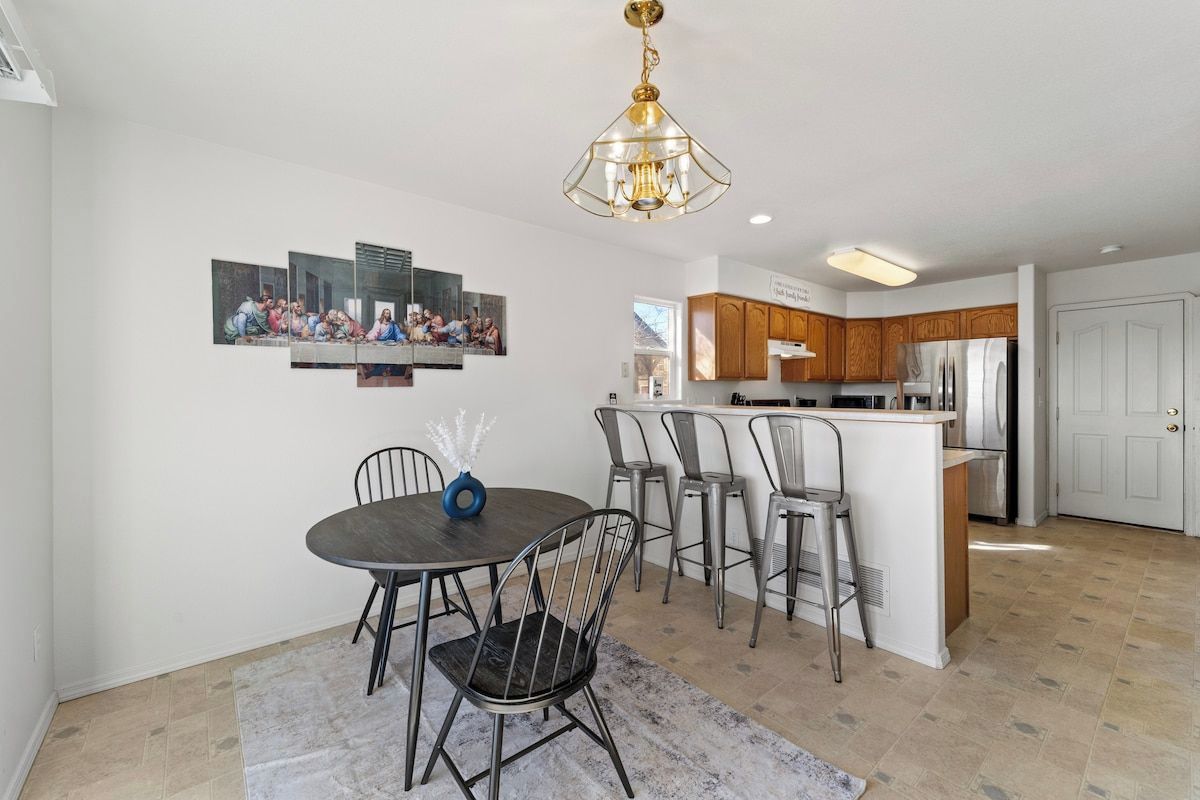 A modern kitchen with a central island, bar stools, and a dining area with a round table and chairs.