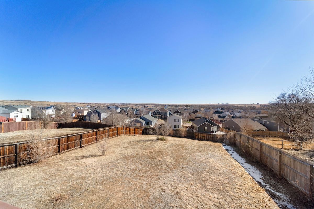Un quartier résidentiel avec des maisons, une cour clôturée et un ciel dégagé.