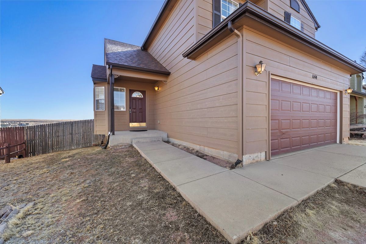A two-story house with a garage, a front door, and a small porch.