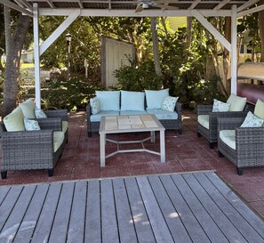 Eine Terrassengaststätte mit Korbmöbeln, einem Tisch und einer Pergola.