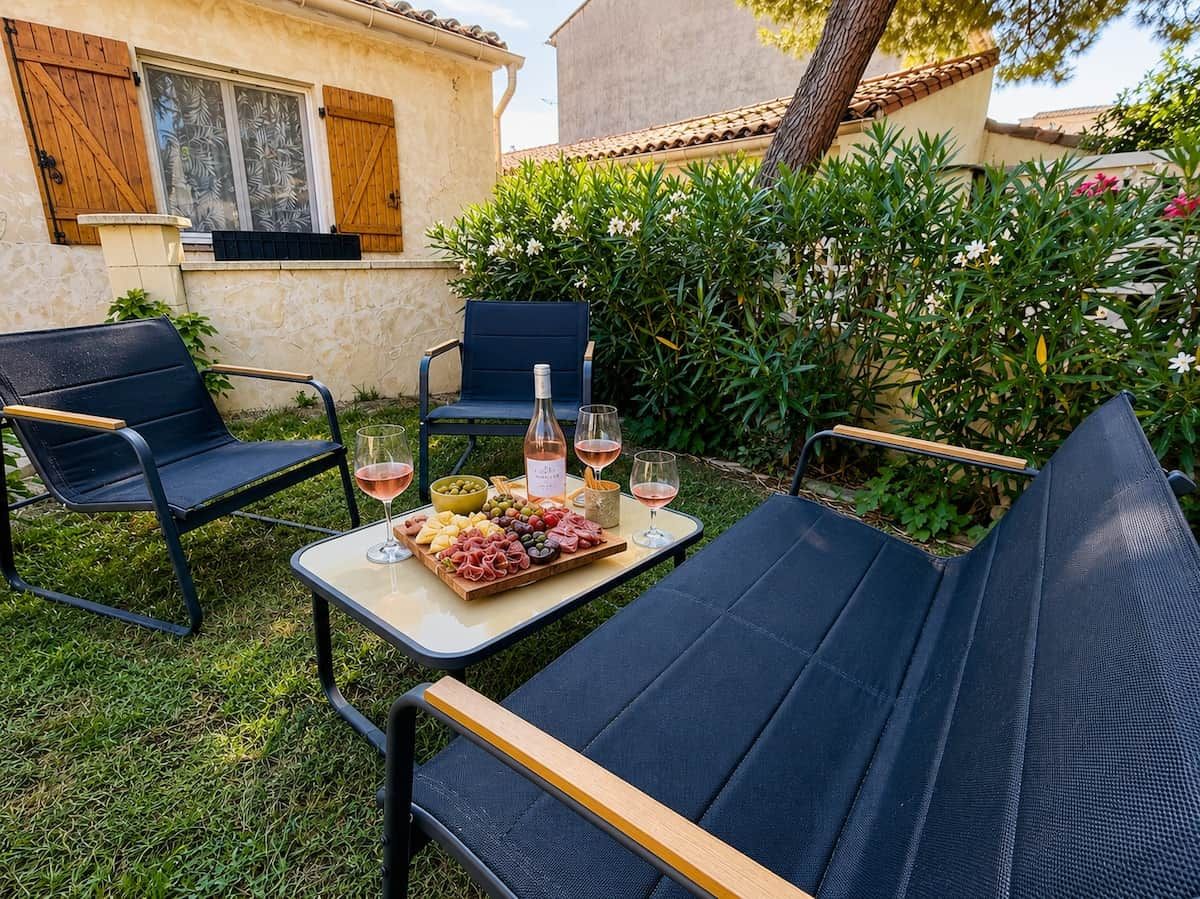 Ein Sitzbereich im Freien mit zwei Stühlen, einem Tisch, einer Weinflasche und einem Weinglas.