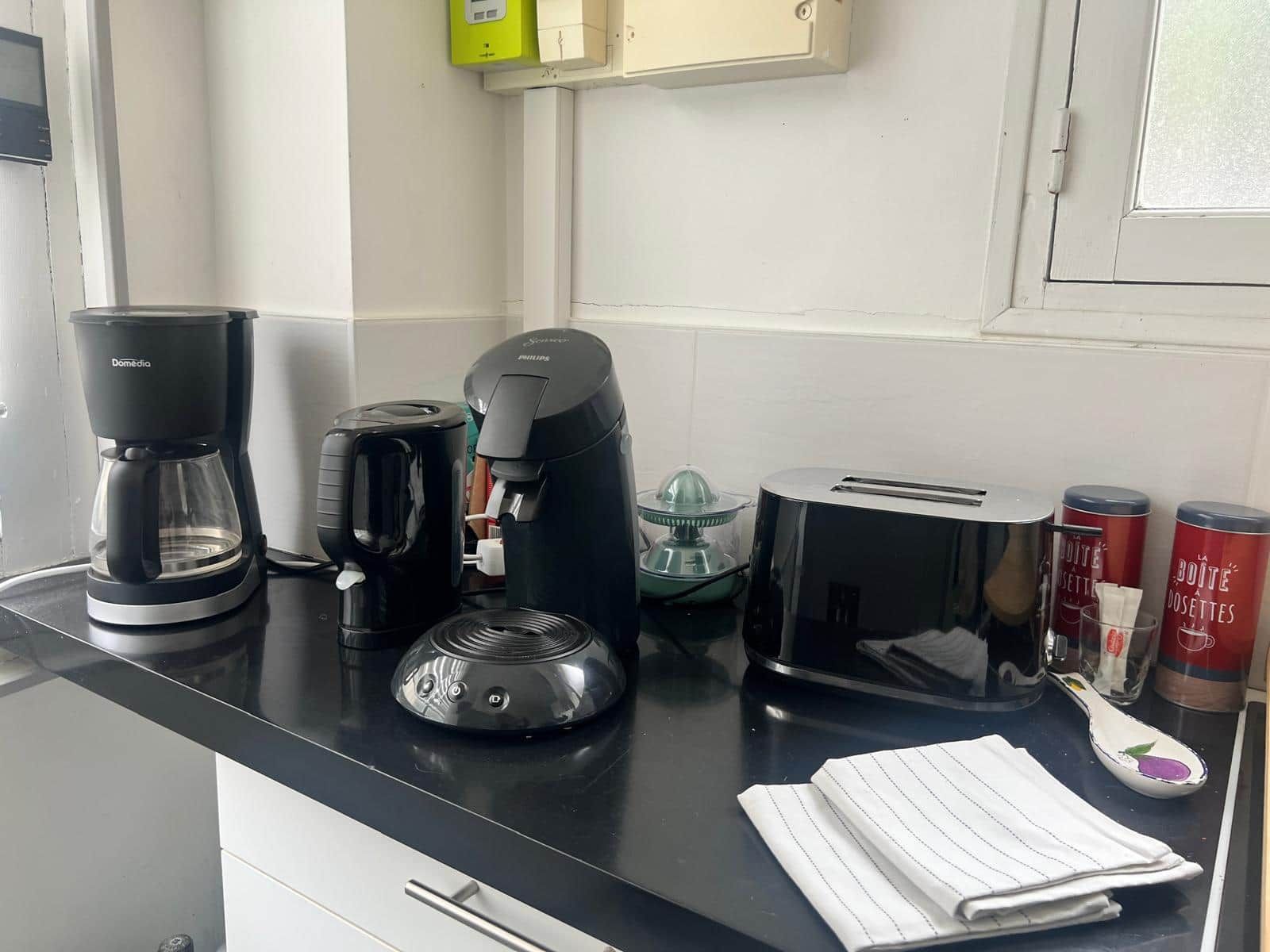 A kitchen counter with a coffee maker, toaster, and a glass container.