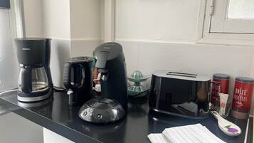 A kitchen counter with a coffee maker, toaster, and a glass container.