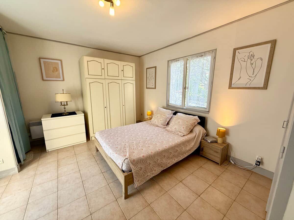 Une chambre à coucher avec un lit, des tables de chevet, une armoire et une fenêtre.