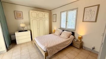 Une chambre à coucher avec un lit, des tables de chevet, une armoire et une fenêtre.