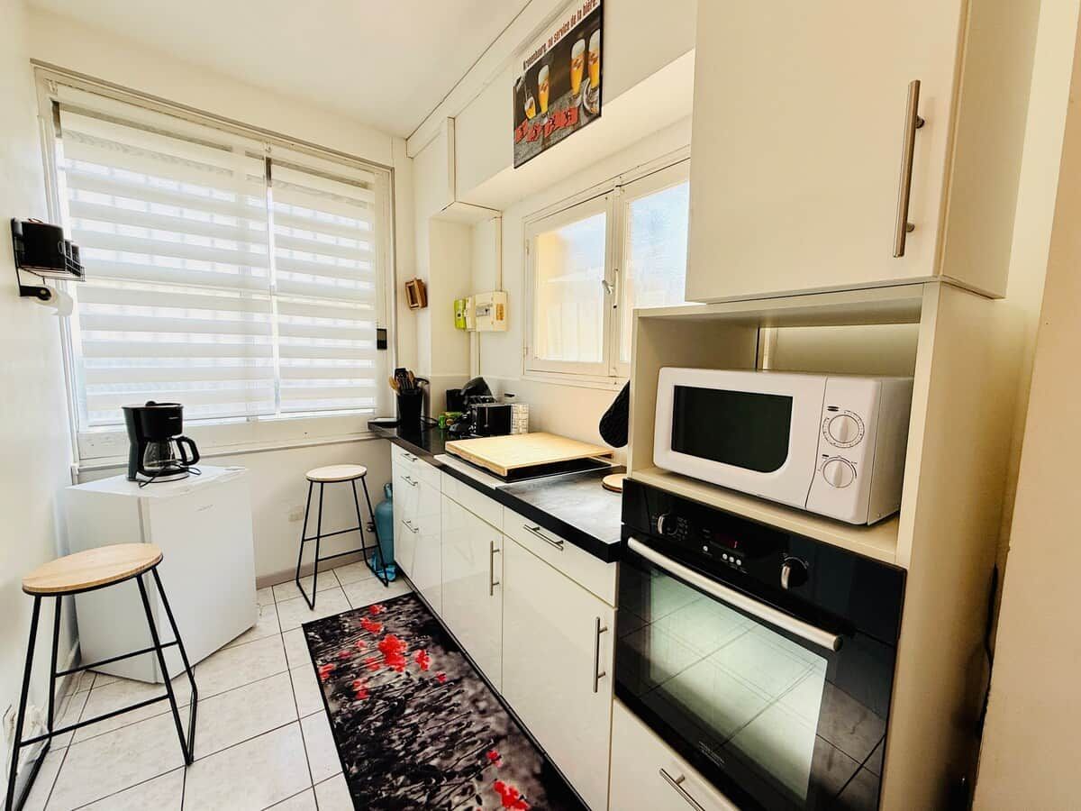 A compact kitchen with a microwave, oven, and a small dining area with stools.