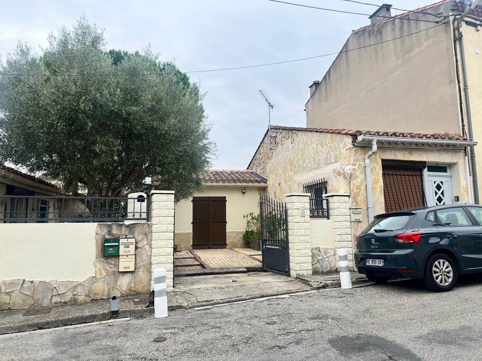 A residential property with a gated entrance, a mailbox, and a parked car.