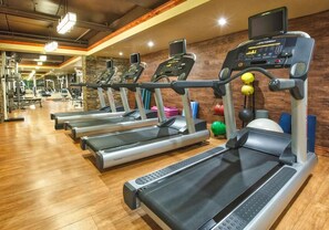 Een sportschool met loopbanden, fitnessballen en gewichten.