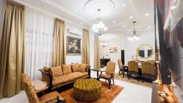 A spacious living room with a sofa set, ottoman, and dining area with chairs and a table.