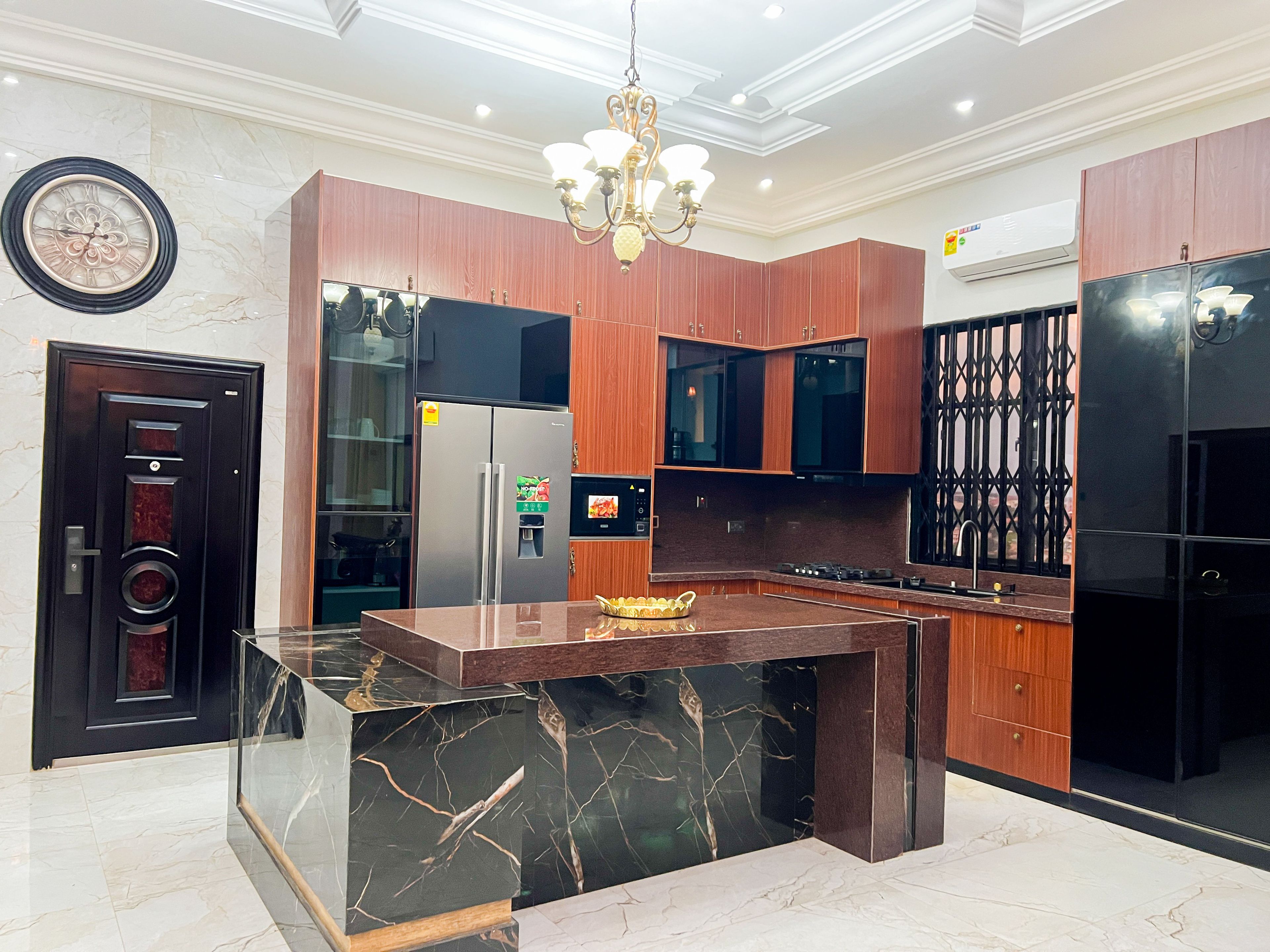 A modern kitchen with a marble island, wooden cabinets, and stainless steel appliances.