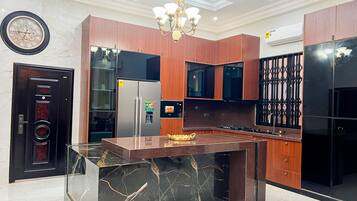 A modern kitchen with a marble island, wooden cabinets, and stainless steel appliances.
