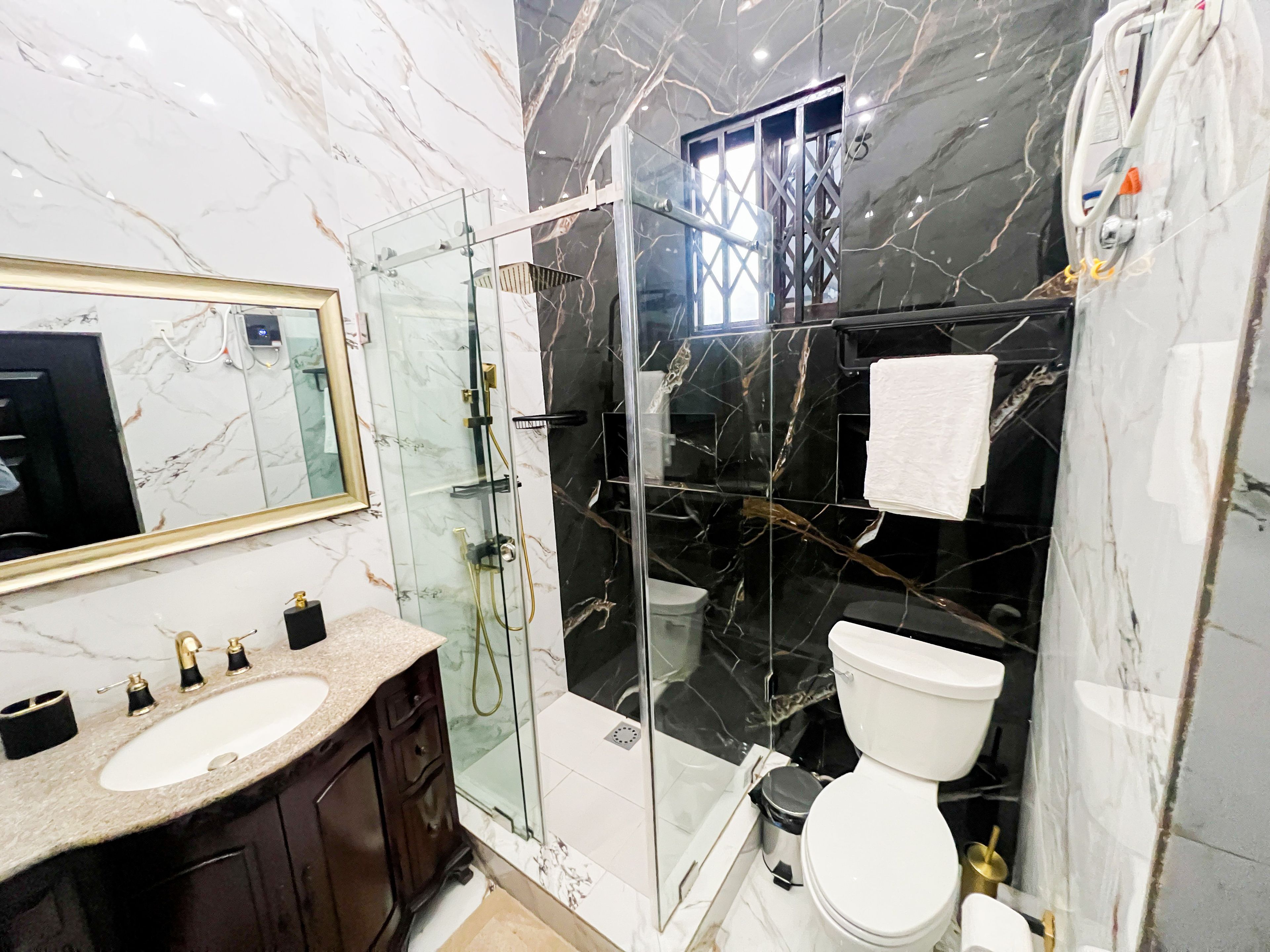 A modern bathroom with a glass-enclosed shower, a white toilet, and a marble vanity with a sink.