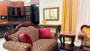 A room with a patterned sofa, a small table, a mirror, and a cabinet.