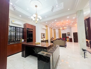 A spacious lobby with a marble floor, a reception desk, a chandelier, and a seating area with patterned upholstery. - AfriBella Executive Suite (Kumasi)
