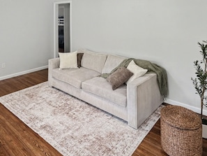 Ein sofas in neutralen Farben, mit einer Decke und Kissen, einem gemusterten Teppich und einem gewebten Korb.
