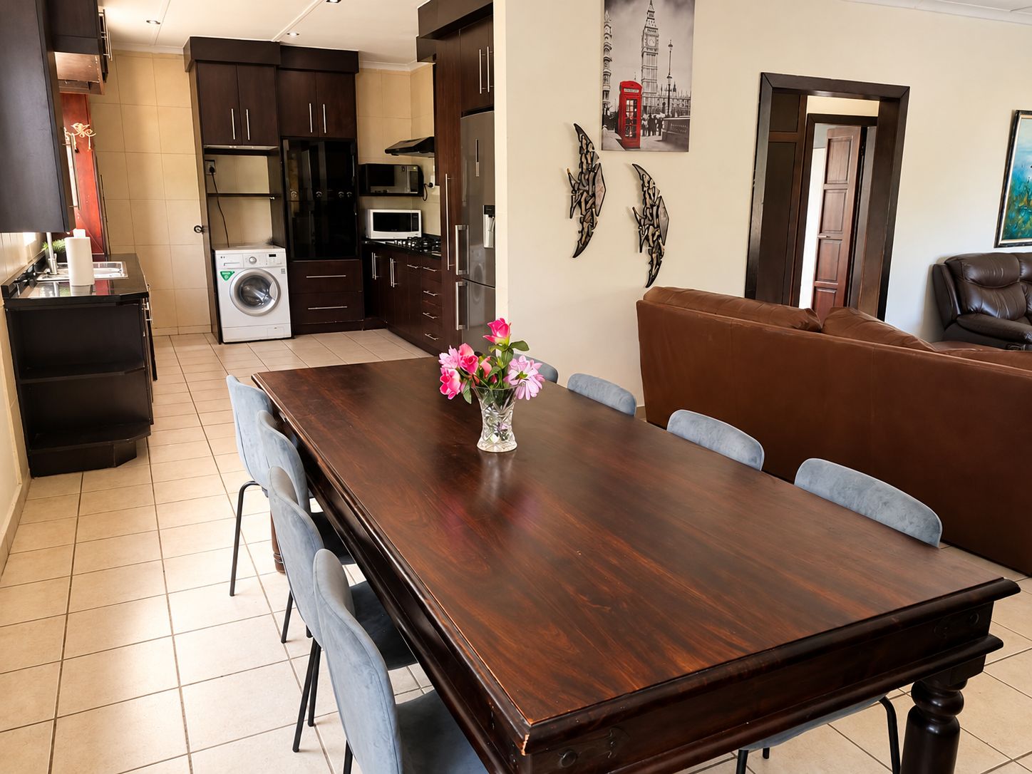 A dining area with a wooden table, chairs, and a vase of flowers.