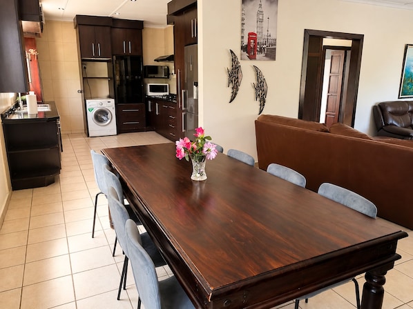 A dining area with a wooden table, chairs, and a vase of flowers.