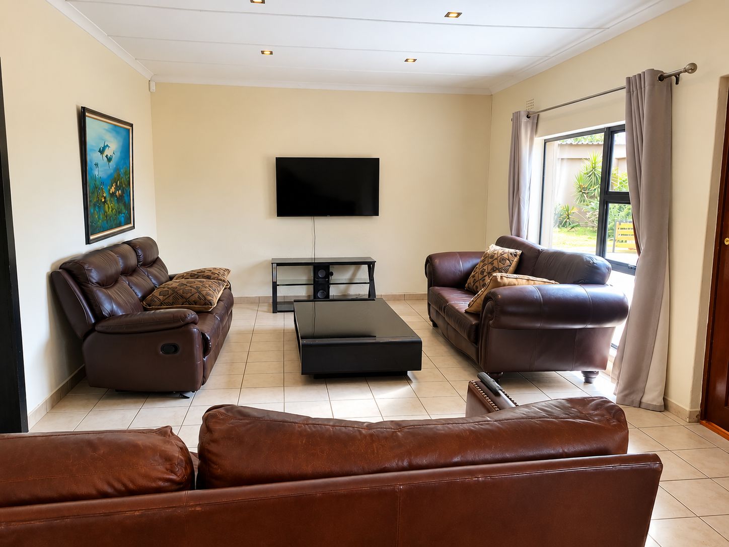 A living room with two leather sofas, a flat-screen TV, and a coffee table.