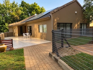 A building with a patio area, a fenced enclosure, and a stone wall. - Perfect 3-bedroom house in Randburg for a relaxing stay (Randburg)