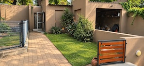 A paved pathway leading to a gated entrance with a small garden area. - Perfect 3-bedroom house in Randburg for a relaxing stay (Randburg)