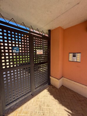 Una entrada protegida por un muro con un letrero, suelo de baldosas y un ventanal pequeño.