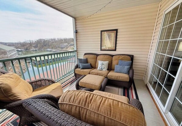 A balcony with wicker furniture and a view of a body of water. - Lakefront condo at lake of the ozarks (Lake Ozark)