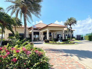 A hotel with a red-tiled roof, palm trees, and a landscaped garden. - Luxury 3-Bedroom Retreat,Pools, Beaches & Snorkeling (Oranjestad)