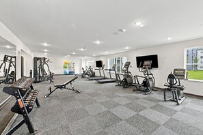 Ein Fitnessstudio mit unterschiedlichen Trainingsgeräten, darunter Laufbänder, Crosstrainer und Kraftgeräte.