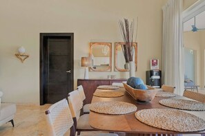 A dining area with a wooden table, woven placemats, and a bowl of round objects. - 4BR Caribbean Villa in Hispaniola (Sosúa)