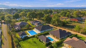 Un barrio residencial con casas, una piscina y vista al mar.